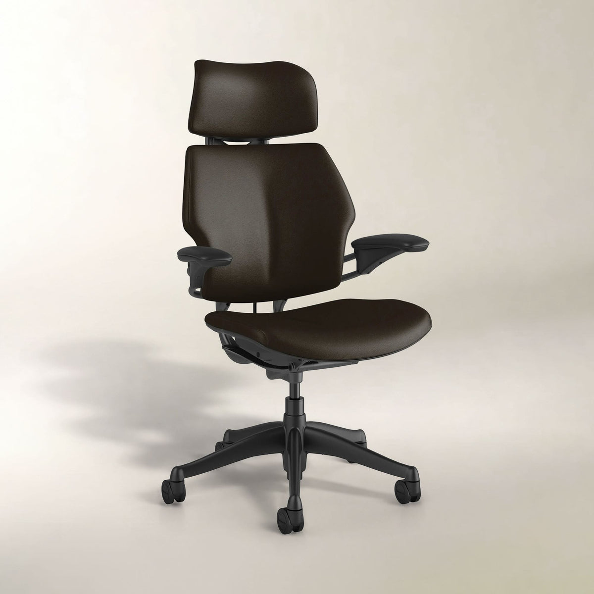 A dark brown ergonomic office chair with a headrest, adjustable armrests, and a black five-star wheeled base, shown against a neutral light beige studio background.