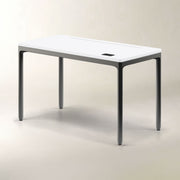 A modern rectangular table with a white top and dark gray legs, shown on a neutral light beige studio background.