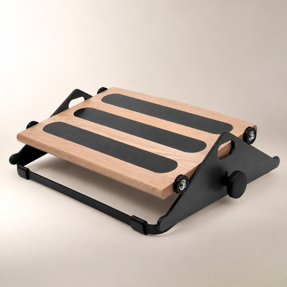A wooden and black adjustable footrest with three non-slip rubber pads on the slope, shown on a neutral beige background.
