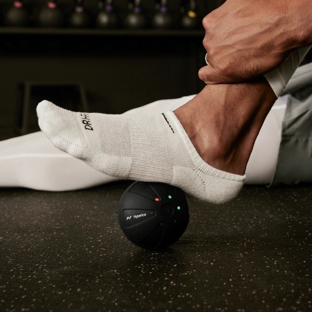Person using a massage ball on their foot with a blurred background