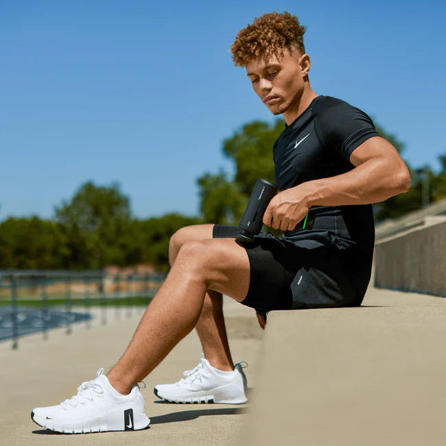 Person in athletic wear sitting outdoors with a clear blue sky