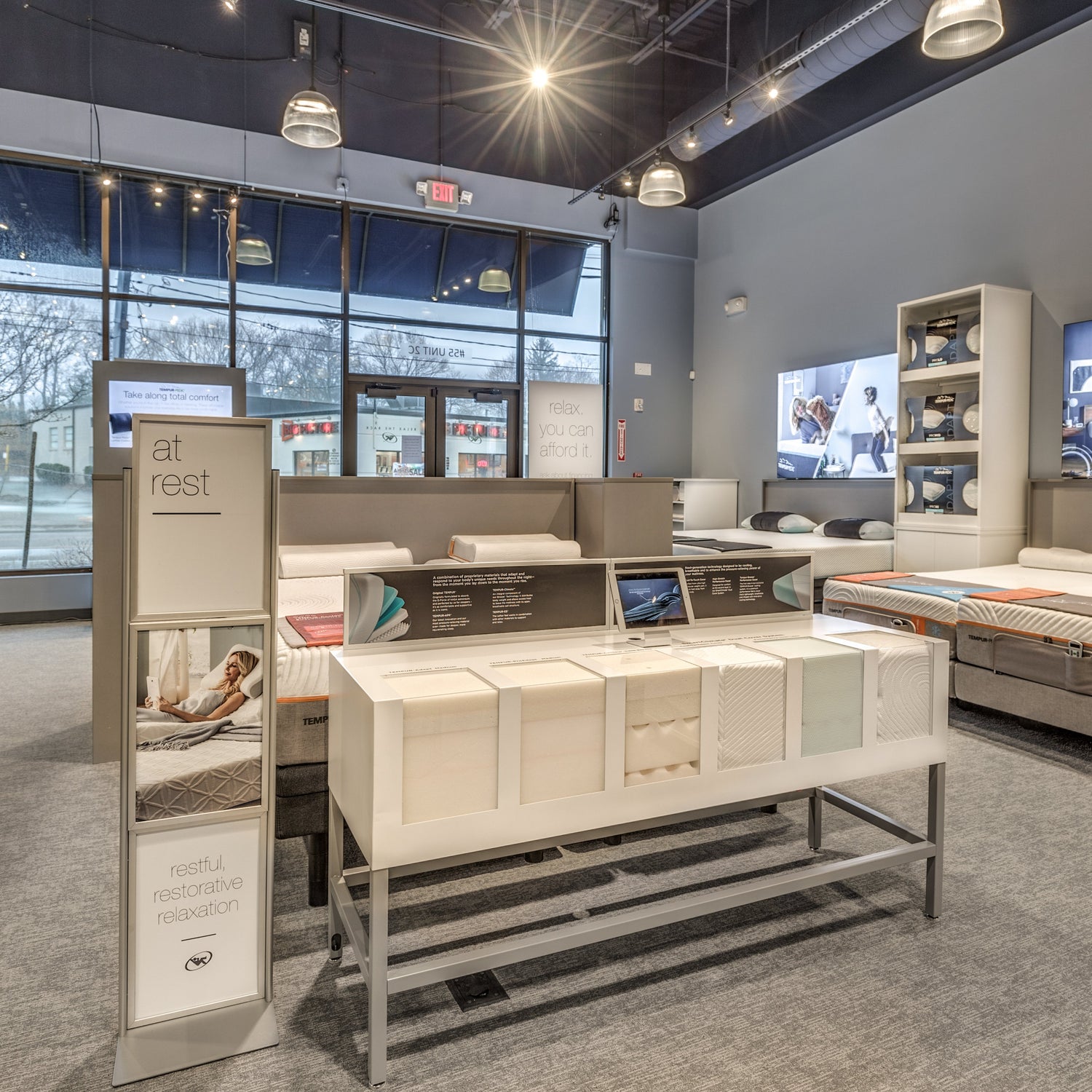 Mattress display in a store with various beds and promotional materials.
