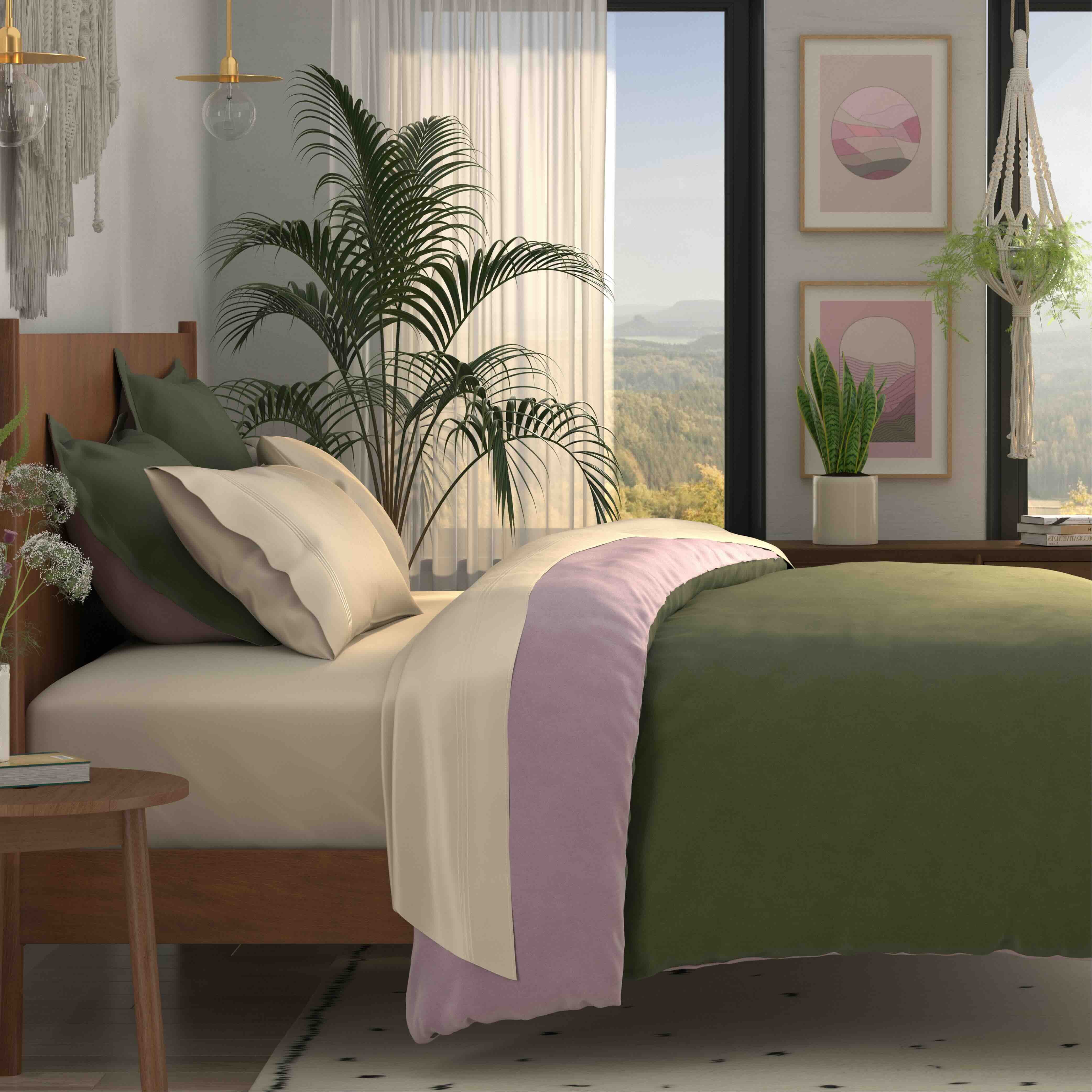 A styled bed in a modern bedroom setting, featuring an olive green duvet, cream and olive green pillows, and a lavender throw blanket. The bed is made of a warm wood frame, set next to a wooden side table with a vase of flowers, and a large potted palm and window with a scenic view are in the background.