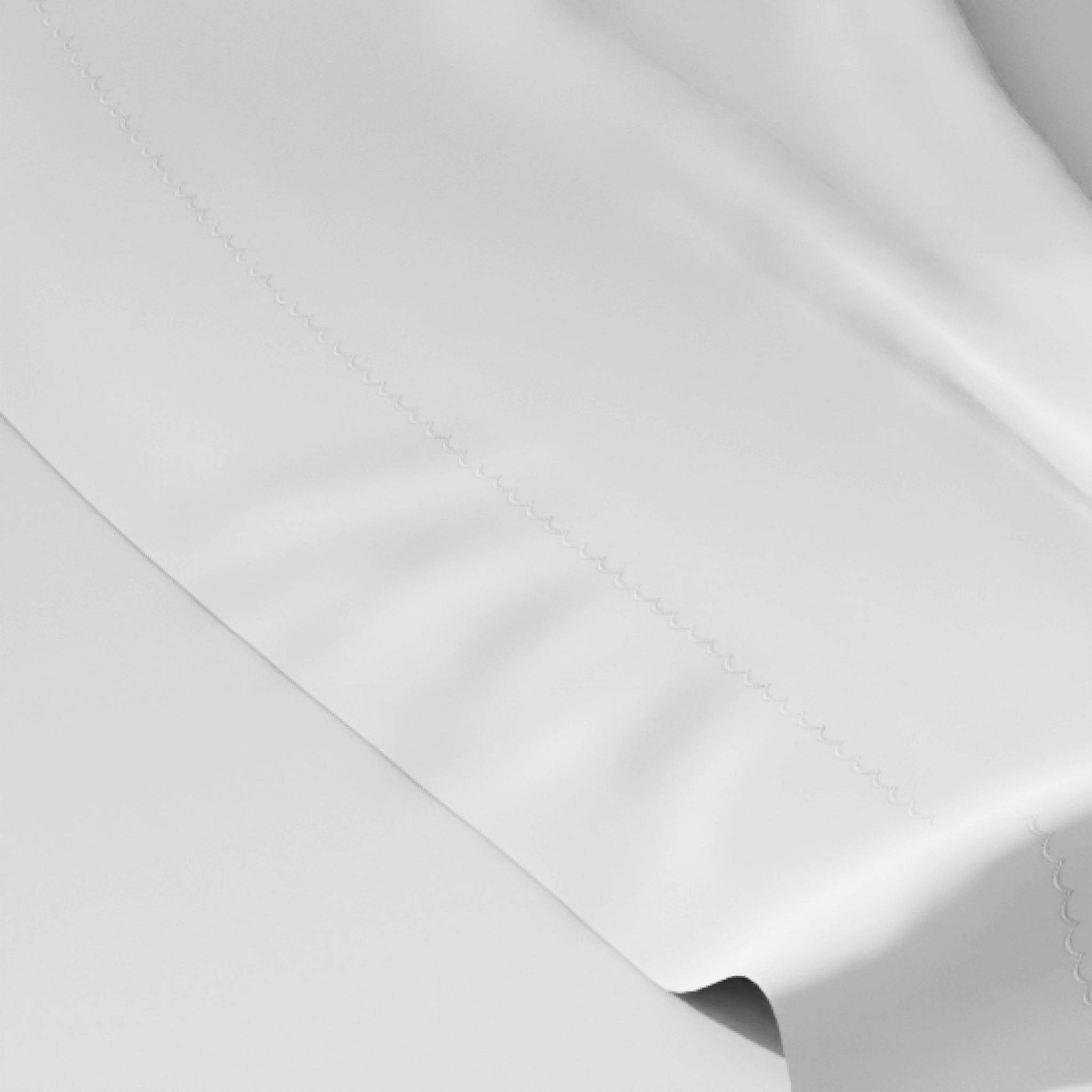A close-up of a white fabric surface with a visible stitched seam and soft folds.