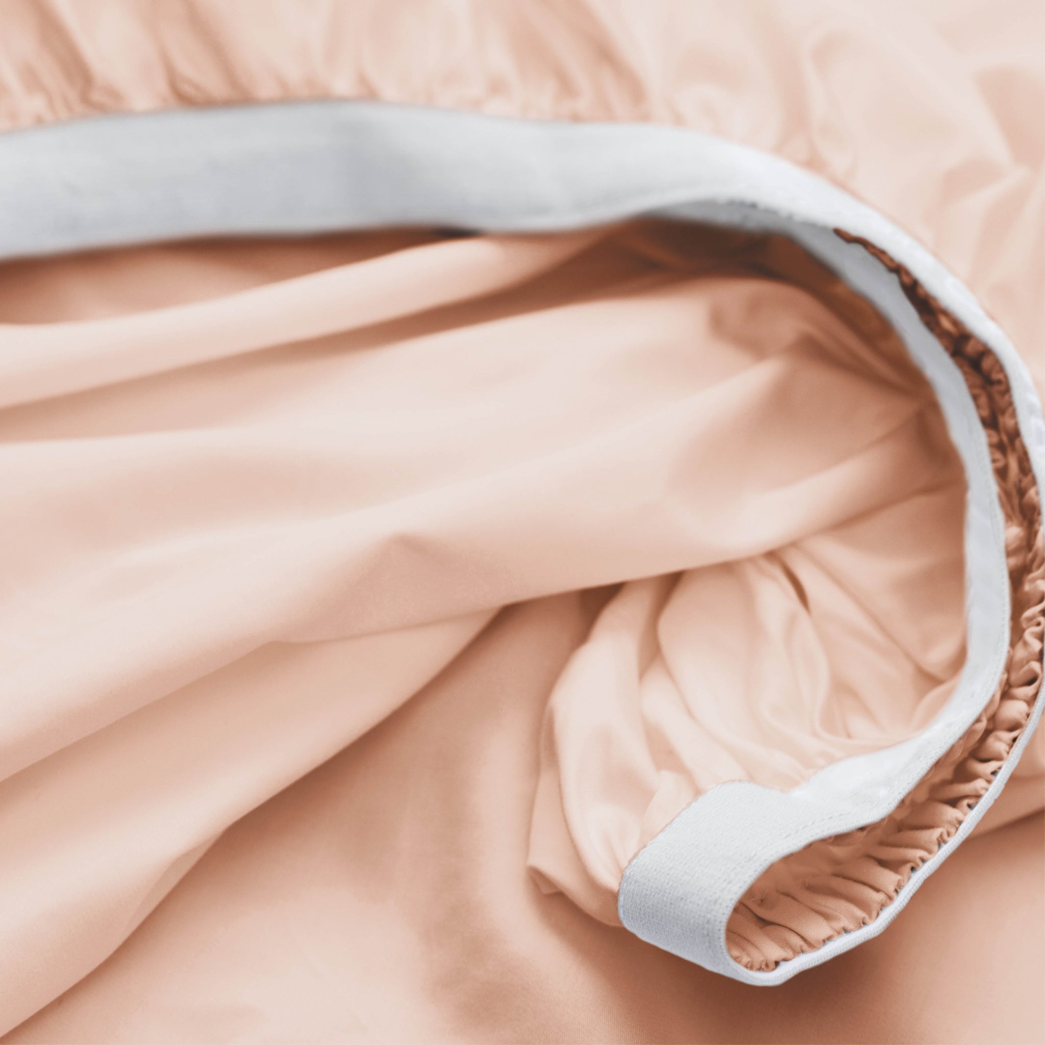 Close-up of a light pink quilt with white trim