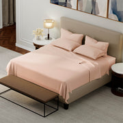 Neatly made bed with pink bedding in a modern bedroom setting.