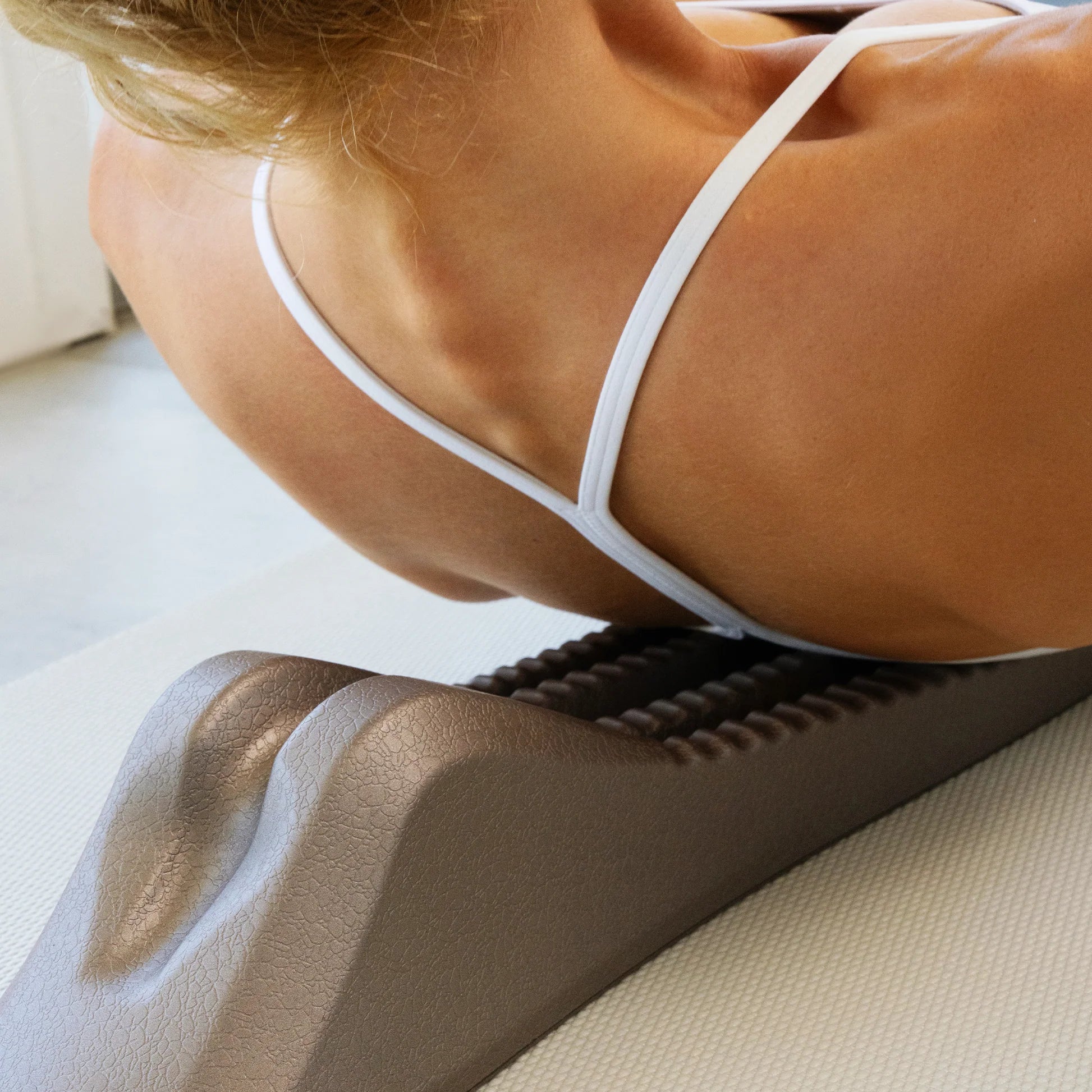 Woman using a gray spine decompression stretcher on her back