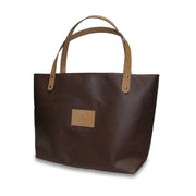 Brown tote bag with leather handle and patch on a white background