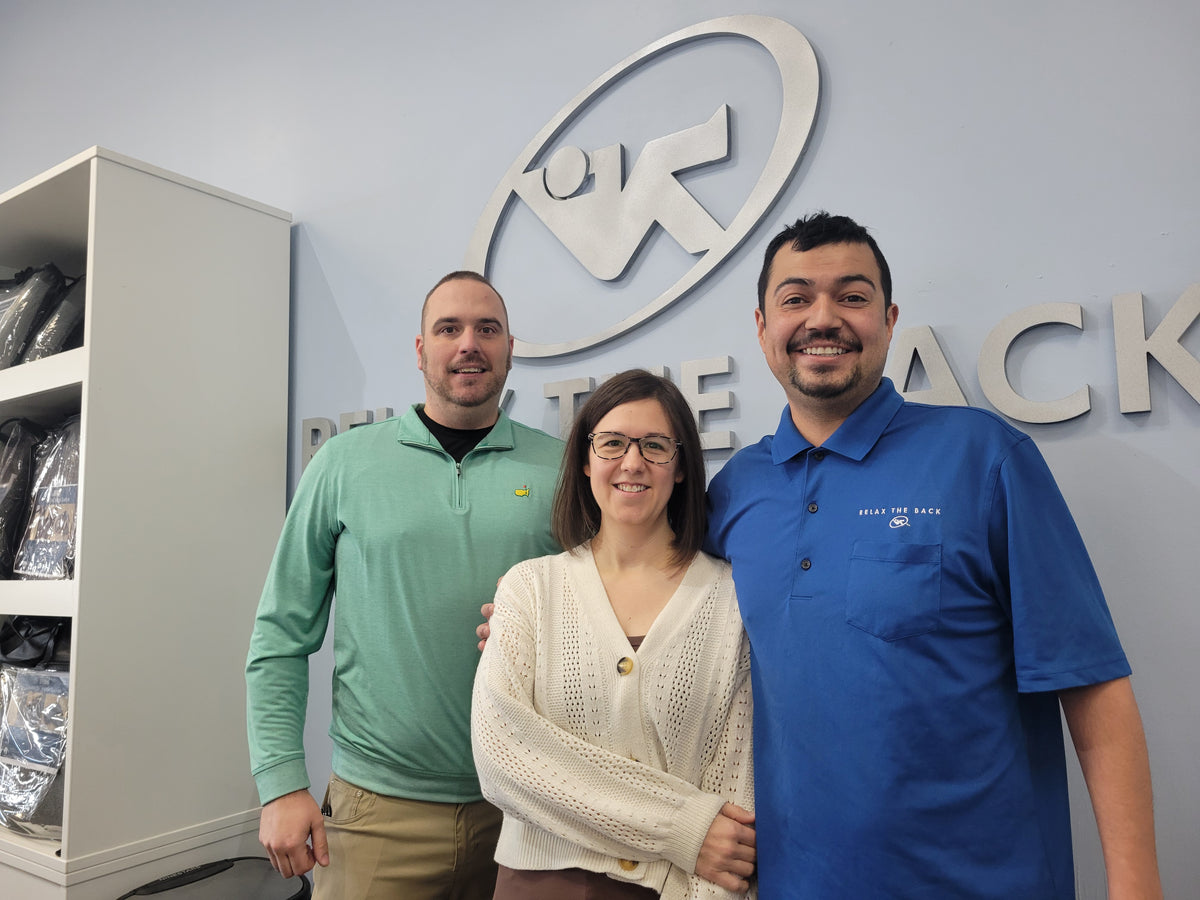 Three people standing in front of a logo on a wall