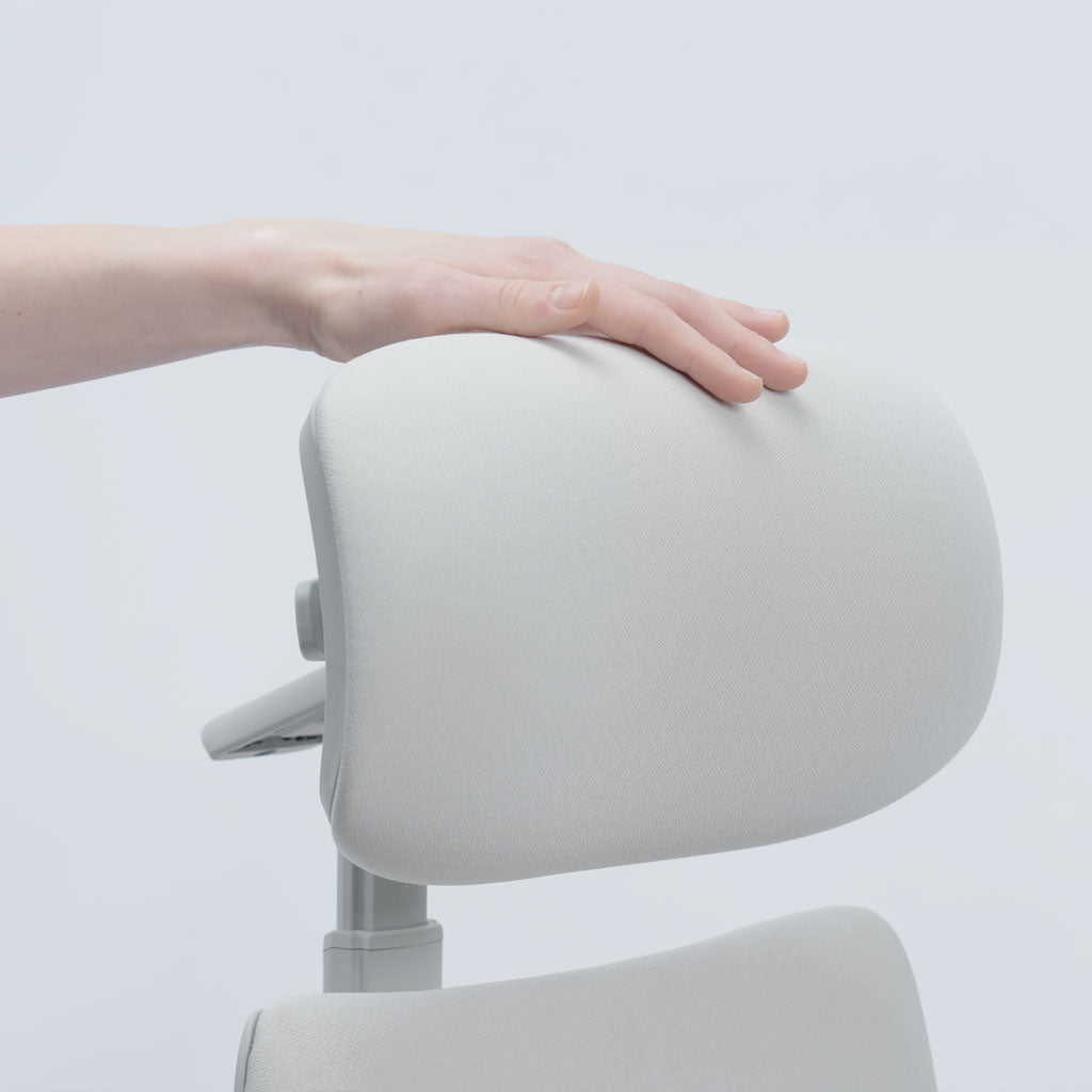 Person adjusting a modern white chair with a neutral background