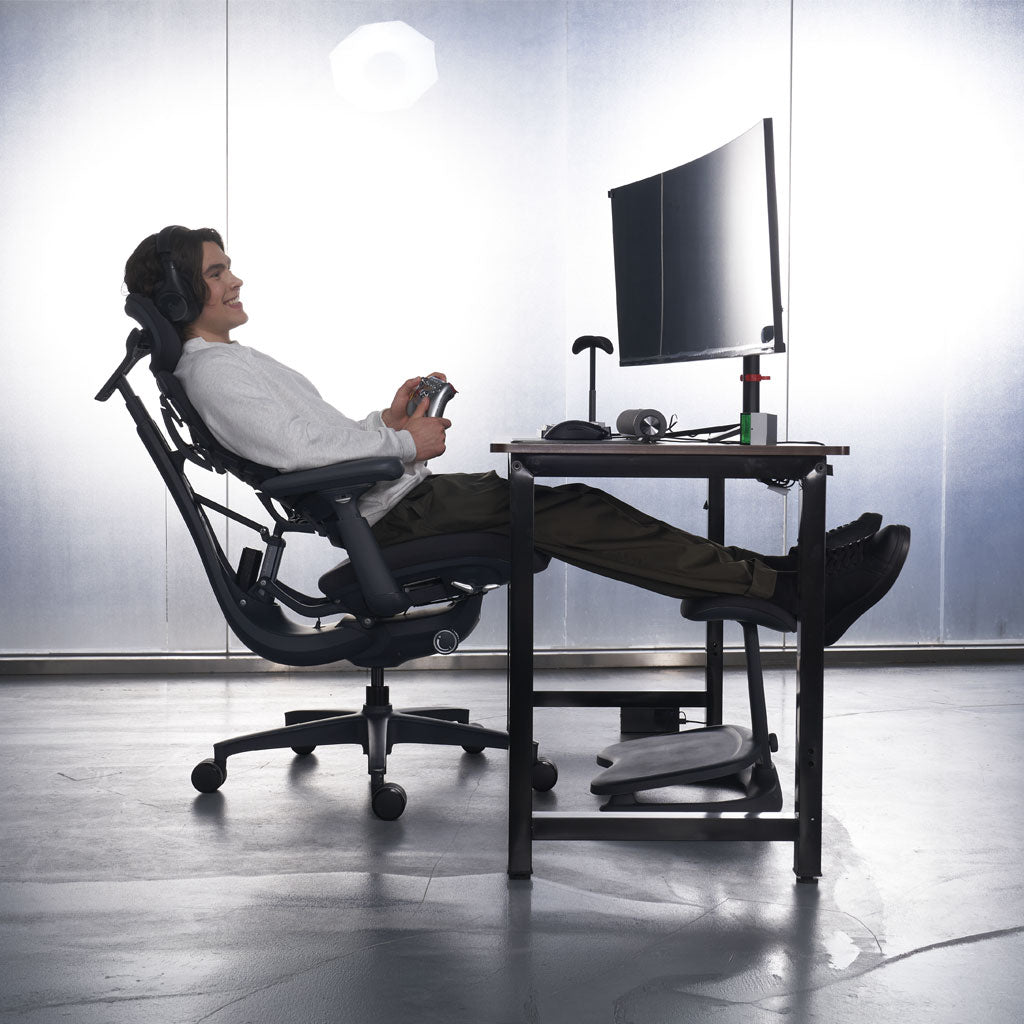 Person using a high-tech office chair with footrest at a desk.