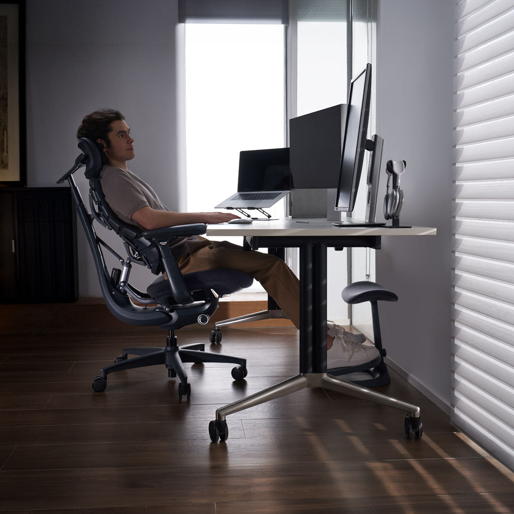 Person sitting at a desk with multiple computer monitors in a dimly lit room.