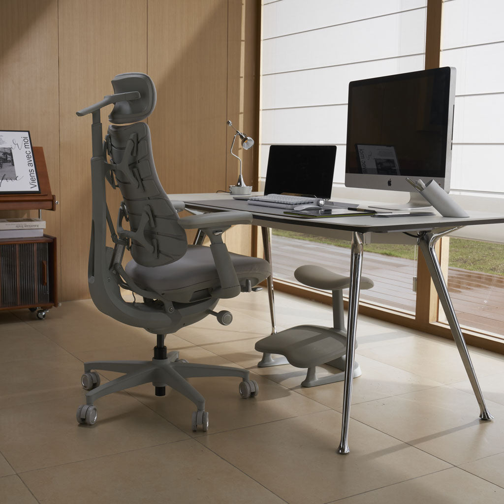 Ergonomic chair in front of a desk with computer setup in a modern office.