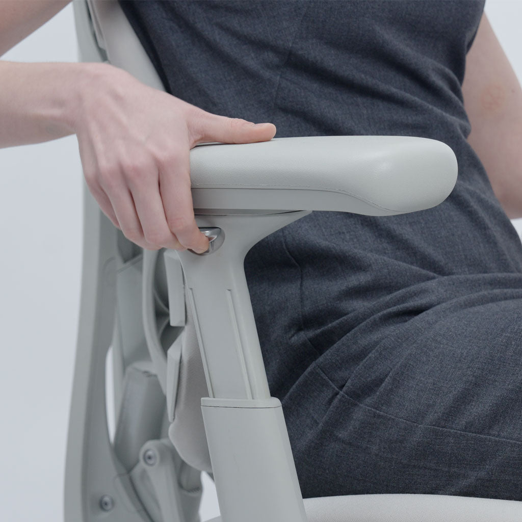Person adjusting a chair with a focus on the armrest and seat mechanism.