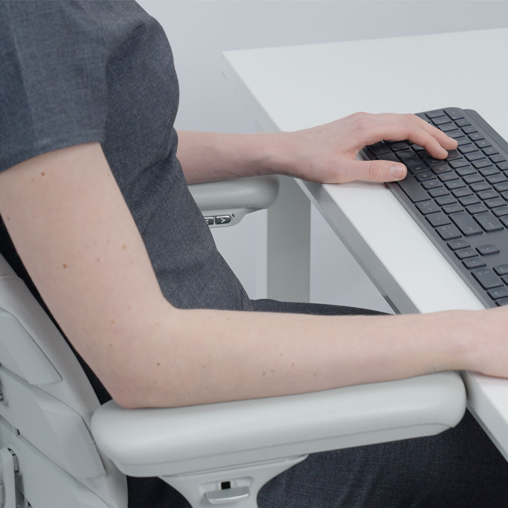 Person using a computer keyboard on a white desk with a neutral background