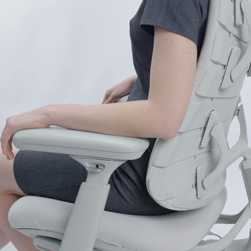 Person sitting on a modern white office chair with a neutral background