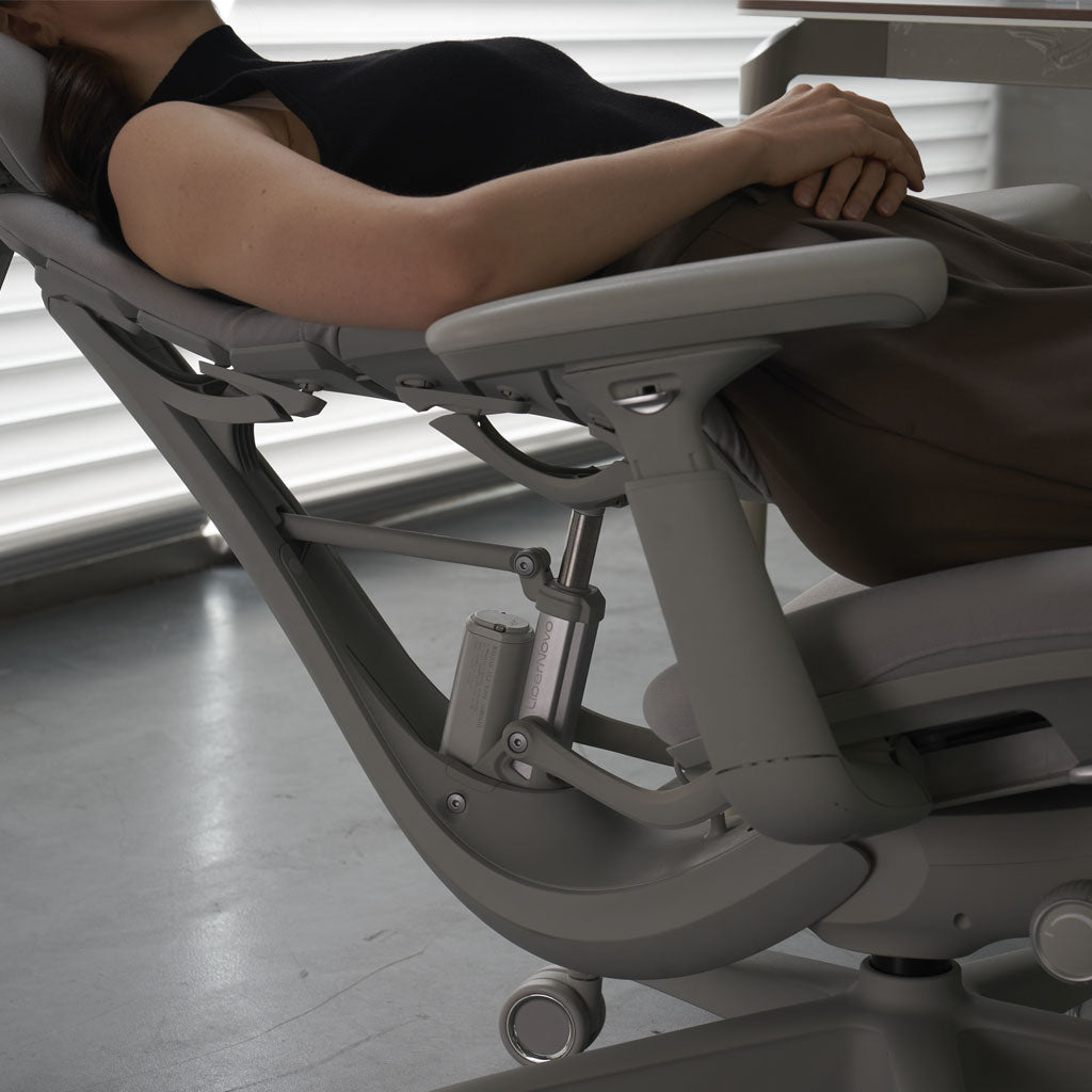Person using a modern ergonomic chair in a minimalistic room.
