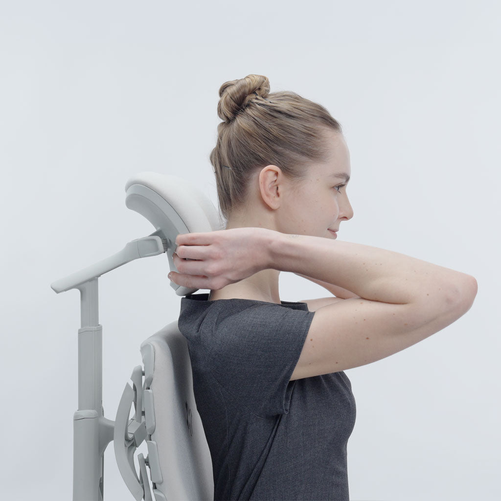 Woman using a neck and shoulder massager against a white background