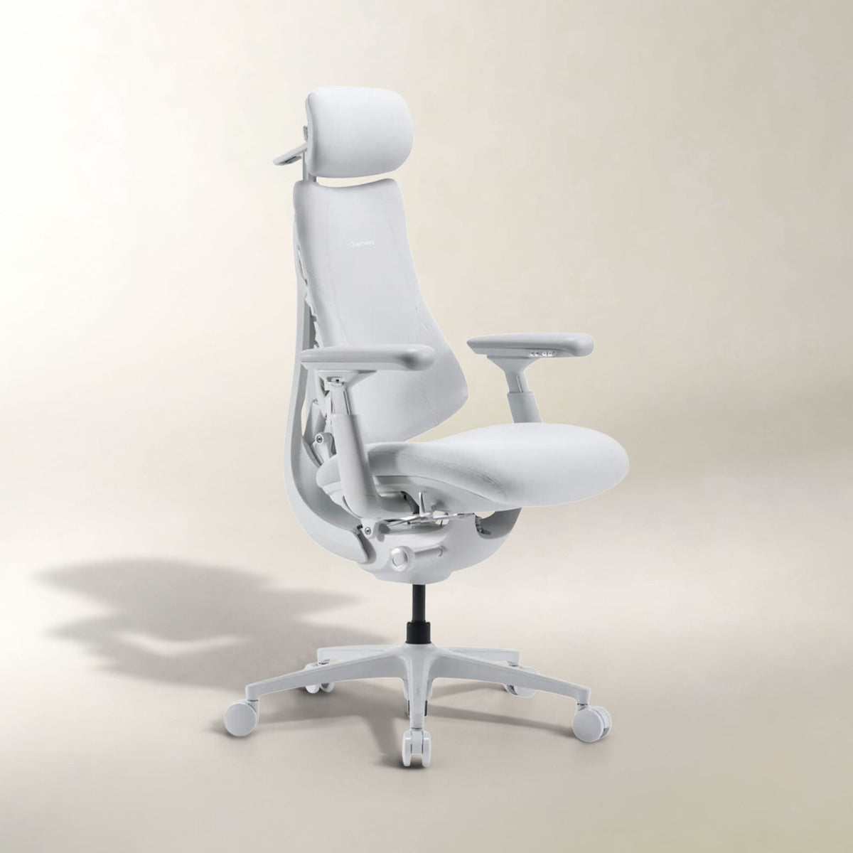 A modern white ergonomic office chair with a headrest, adjustable armrests, and a five-wheel base, photographed against a clean beige studio background.