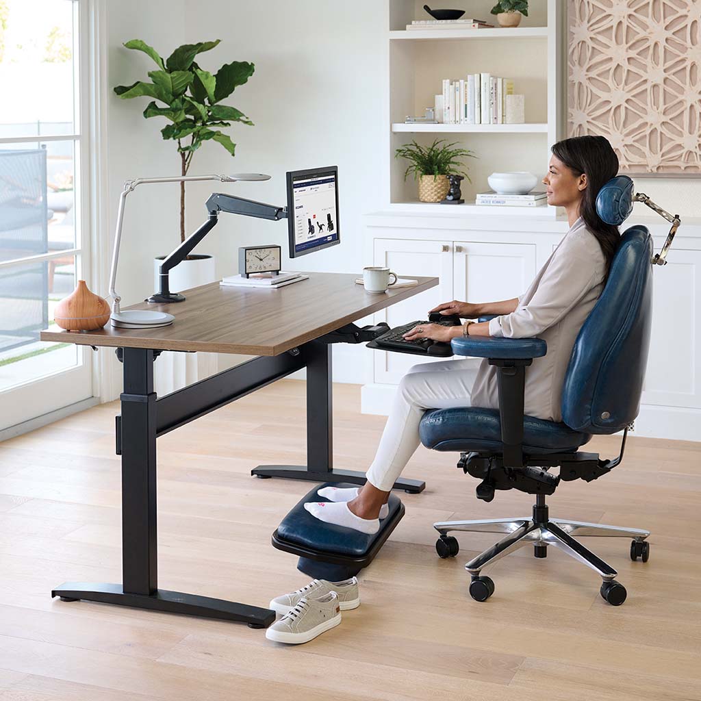 Person using a standing desk with a footrest in a home office setting