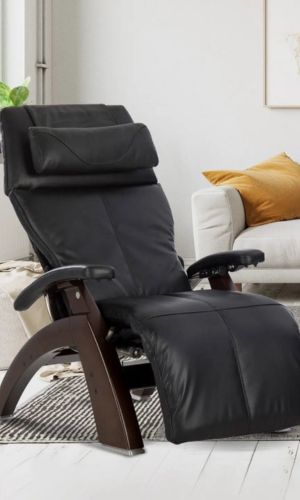 Black recliner chair in a living room setting with a white sofa and yellow pillow.