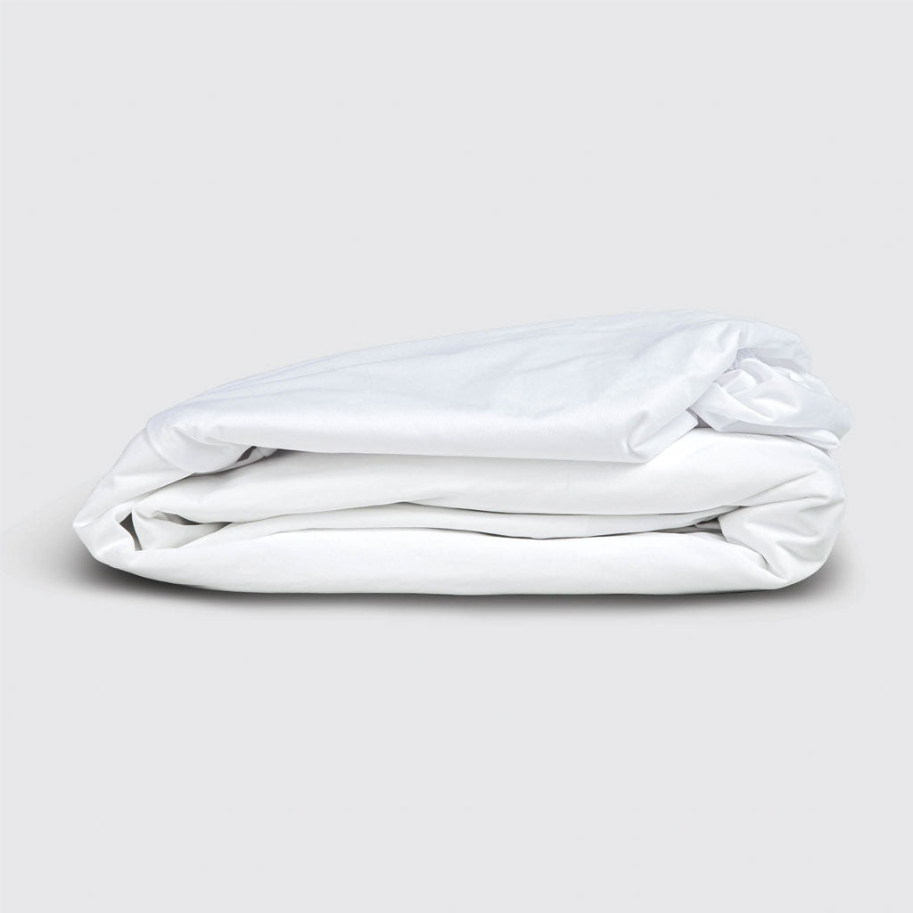 Folded white mattress protector on a light gray background