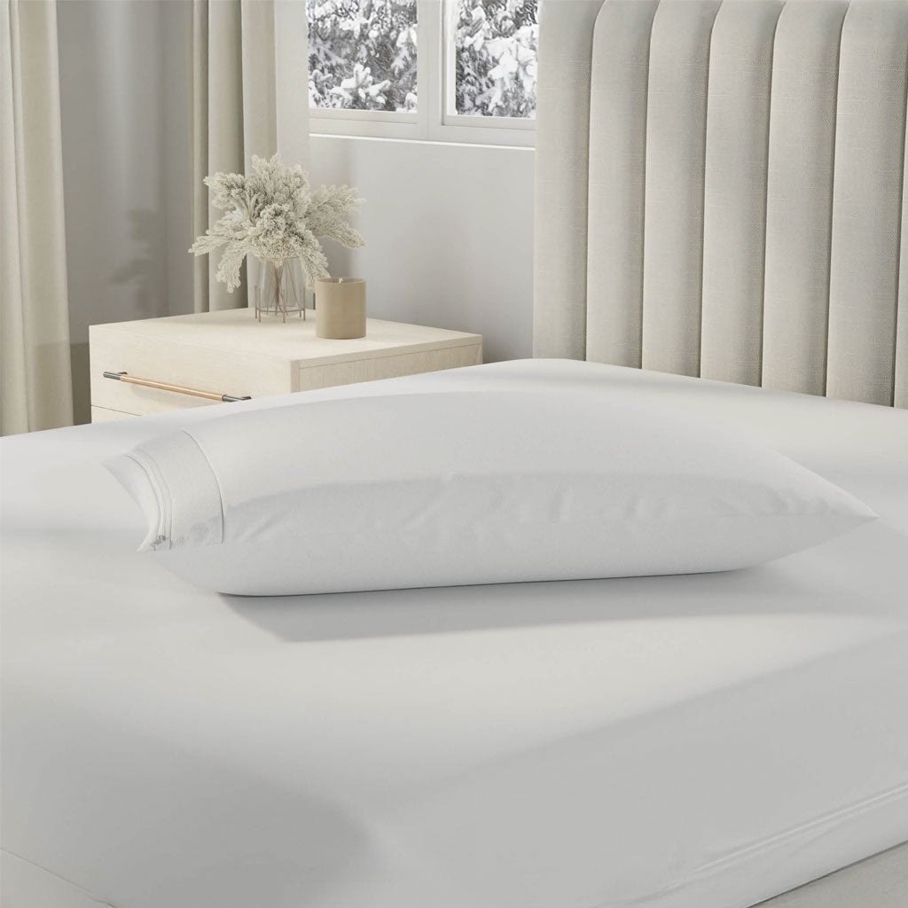 White pillow on a bed in a bedroom with a window and desk in the background