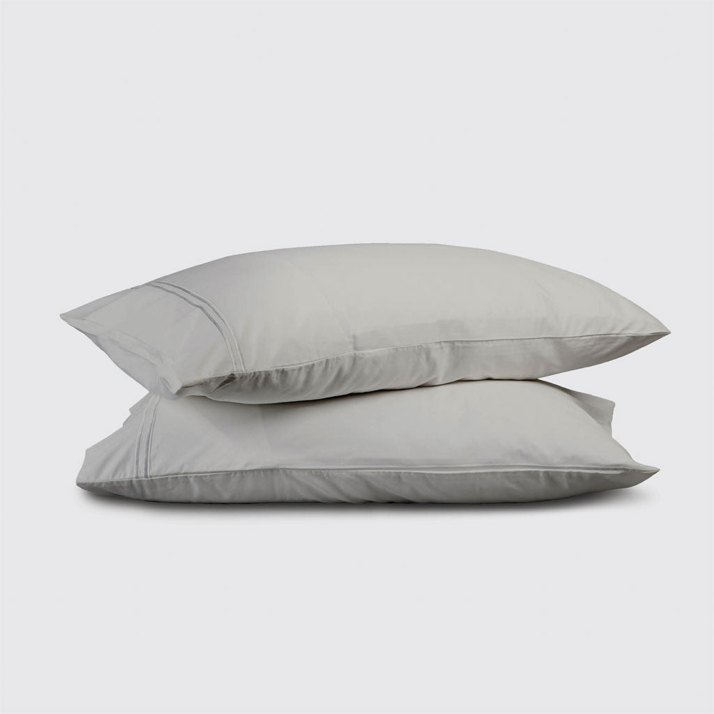 Two light gray pillows stacked on a white background