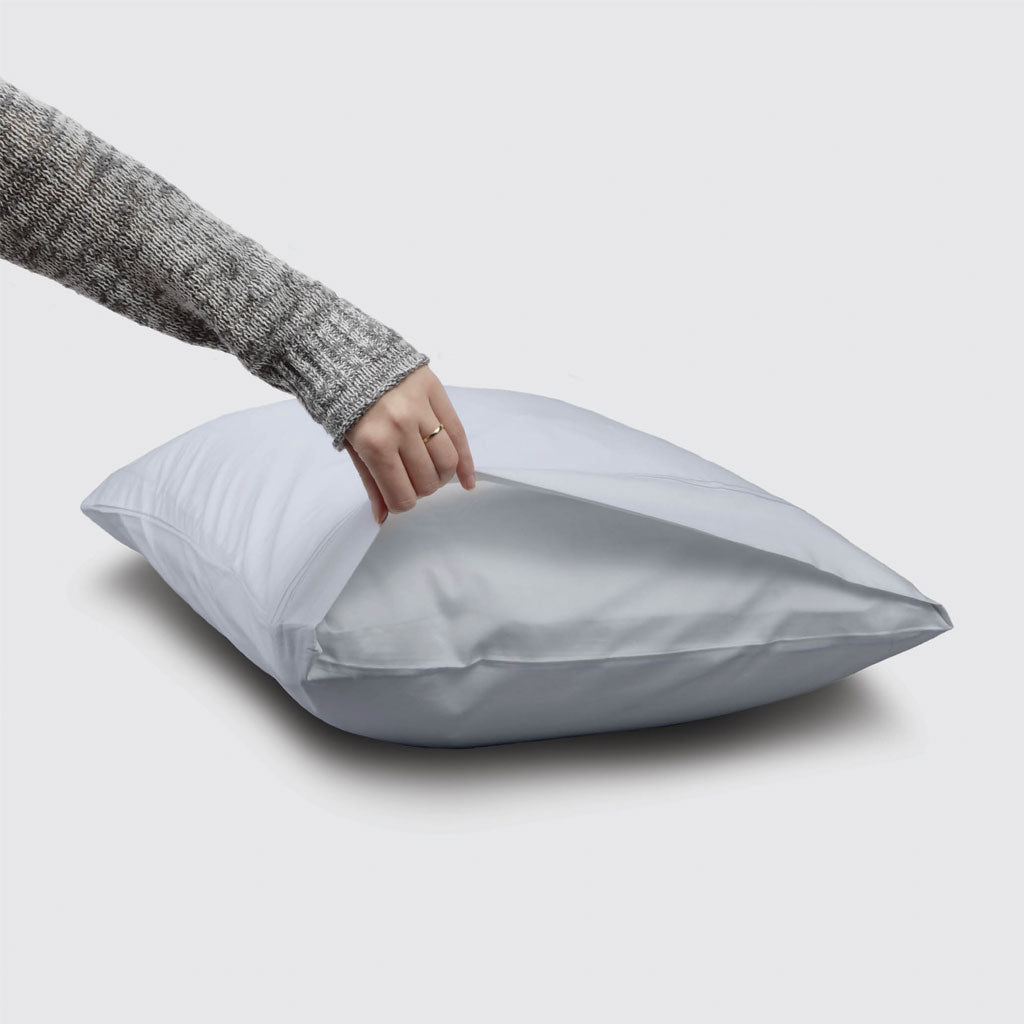 Person holding a white pillow against a light gray background