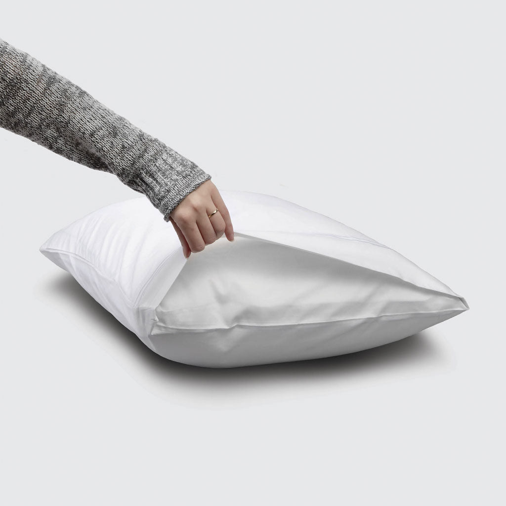 Person holding a white pillowcase on a light gray background