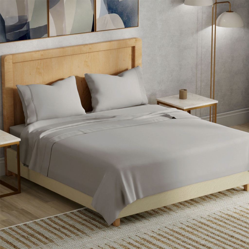 Bedroom with a wooden bed frame and gray bedding, side tables, and abstract art on the wall.