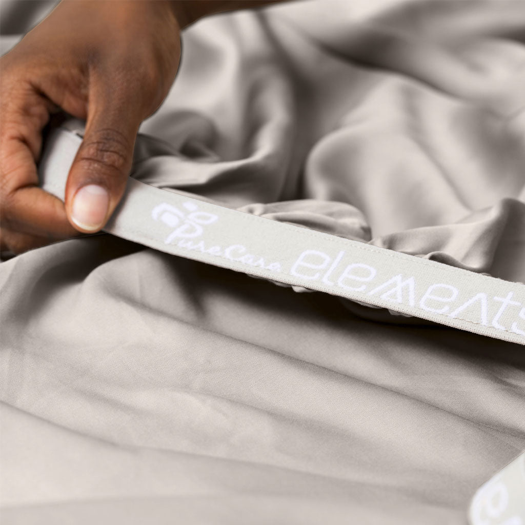 Person holding a gray fitted sheet