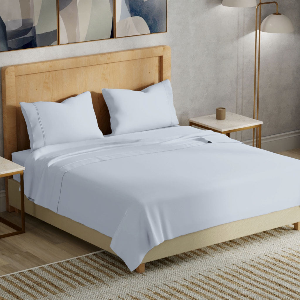Neatly made bed with light blue bedding in a bedroom setting.