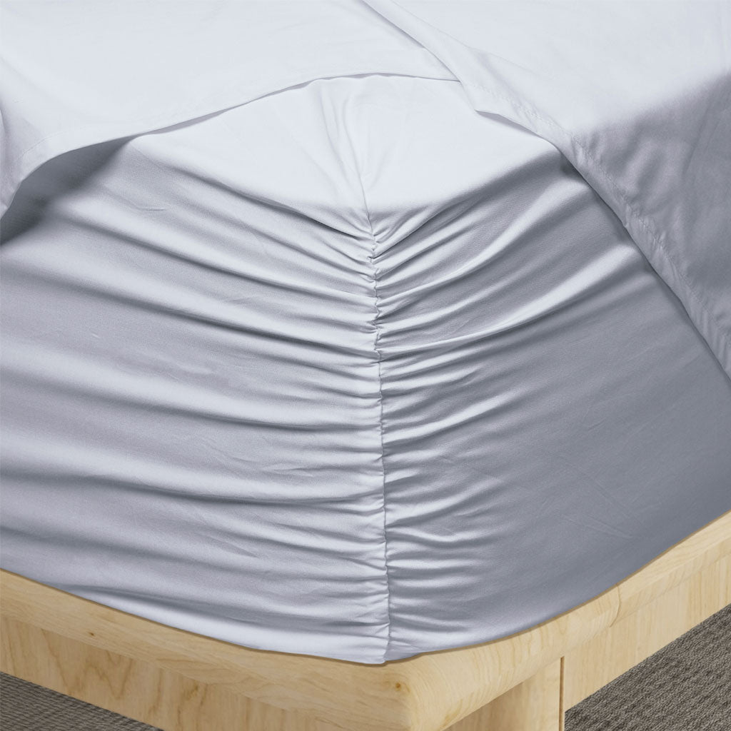 Light blue fitted sheet on a wooden bed frame