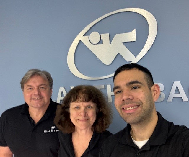Three people posing in front of a logo on a wall