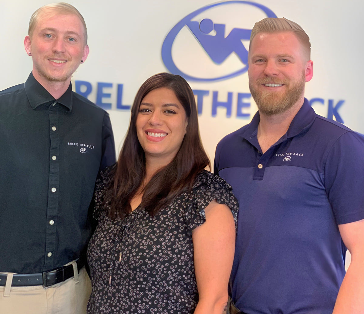 Three people standing together in front of a logo with 'Relieve the Back' text.
