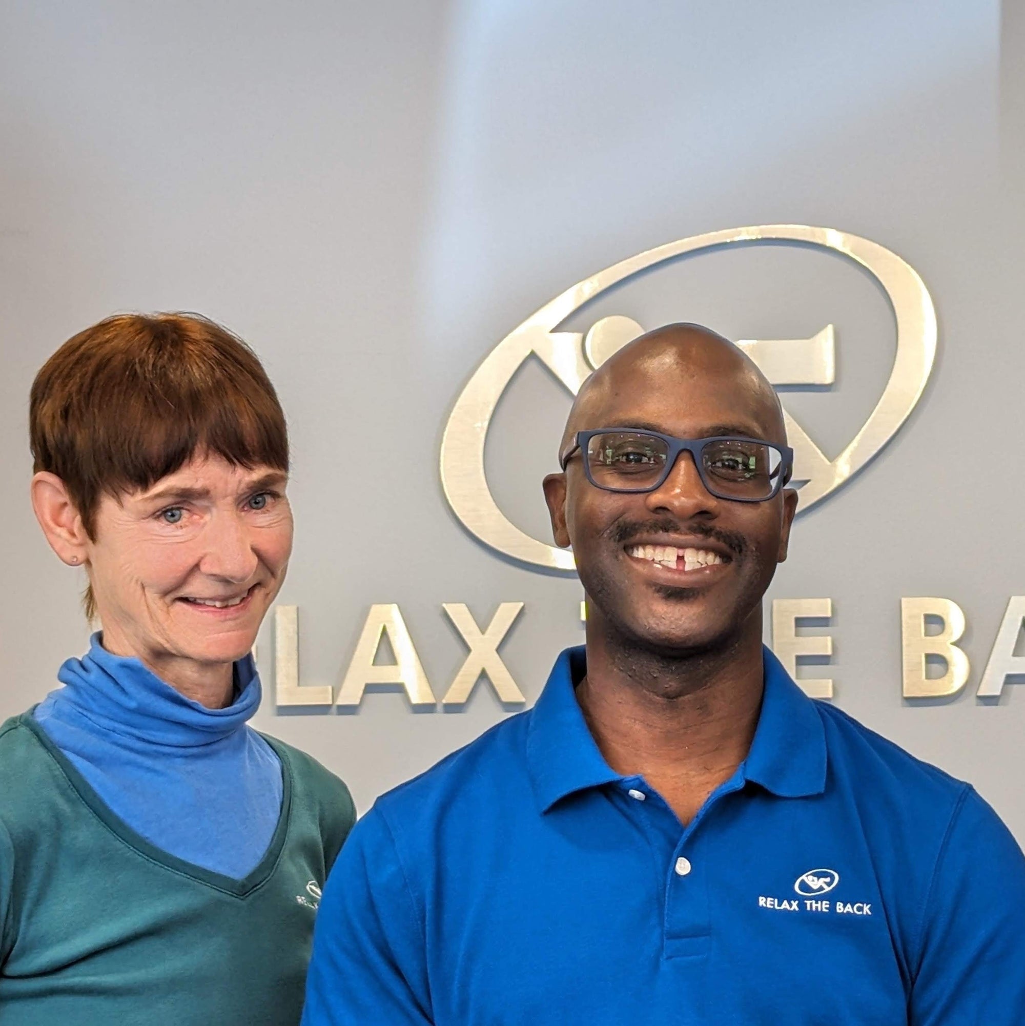 Two people standing in front of a logo with 'Relax the Back' branding.
