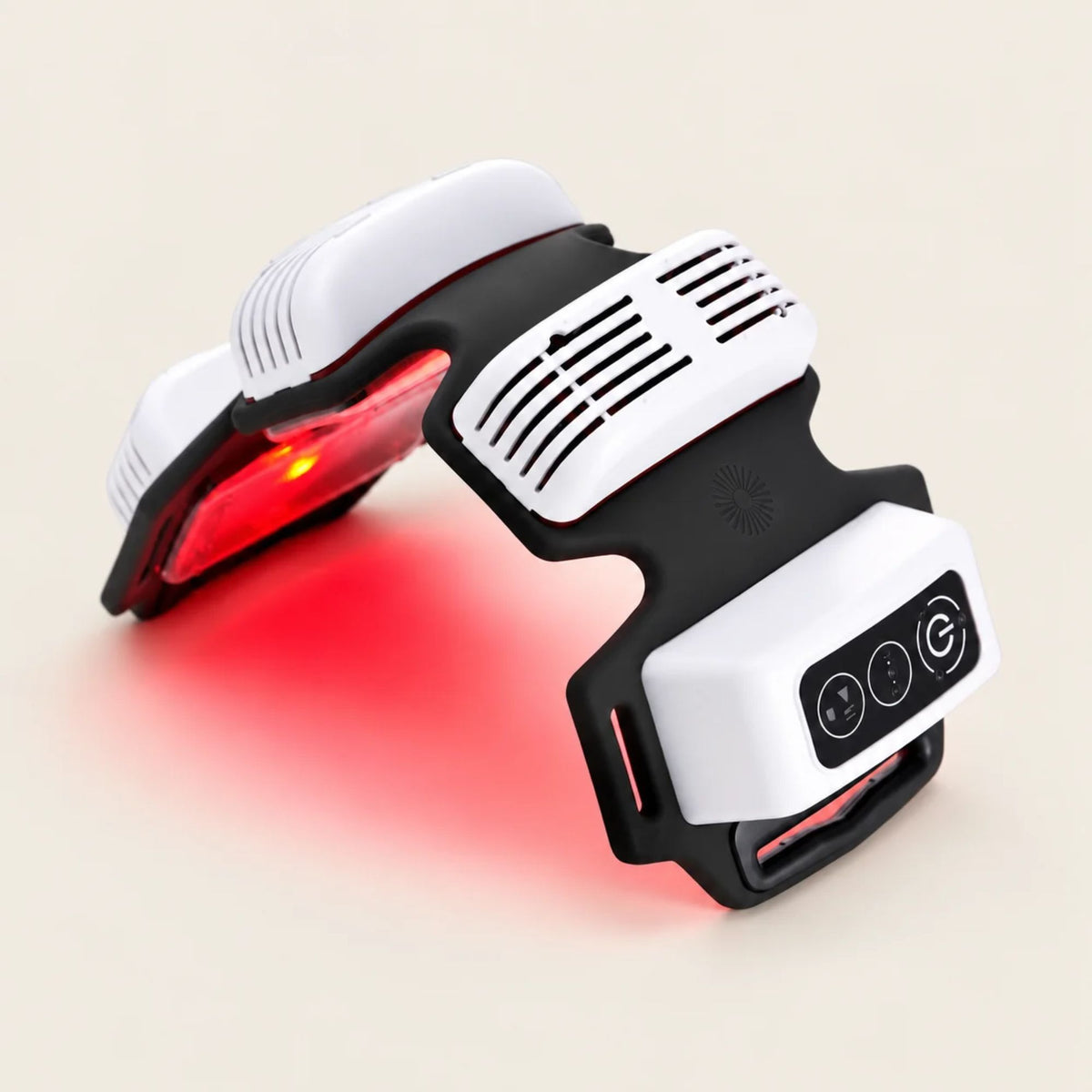 A white and black wearable red light therapy device with a glowing red light therapy panel, shown on a beige studio background with a red glow.