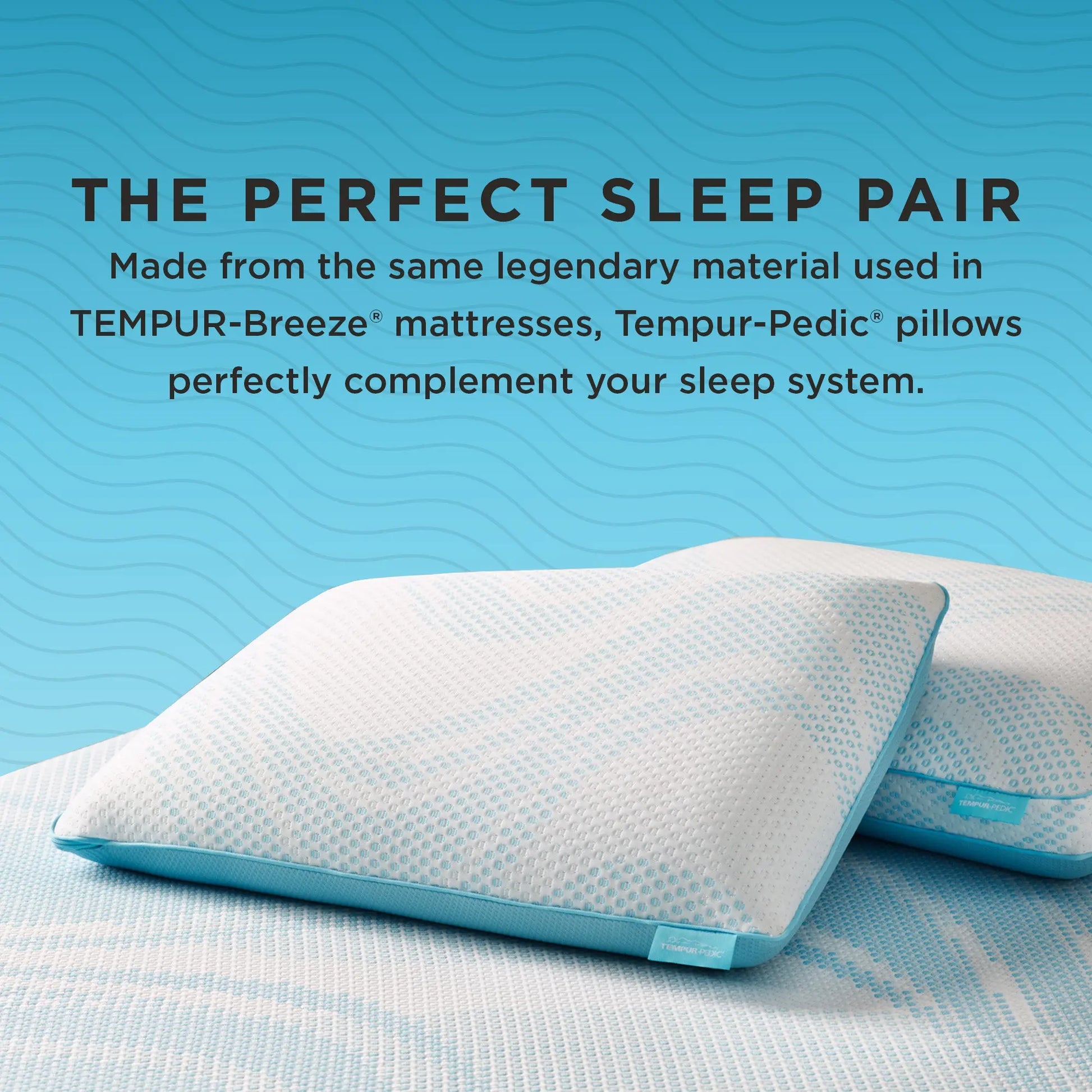 Two TEMPUR-Pedic Breeze® pillows rest on a matching mattress, featuring white and blue cooling covers. Text above them highlights that the pillows are made from the same legendary material as TEMPUR-Breeze® mattresses, creating the perfect sleep pair.