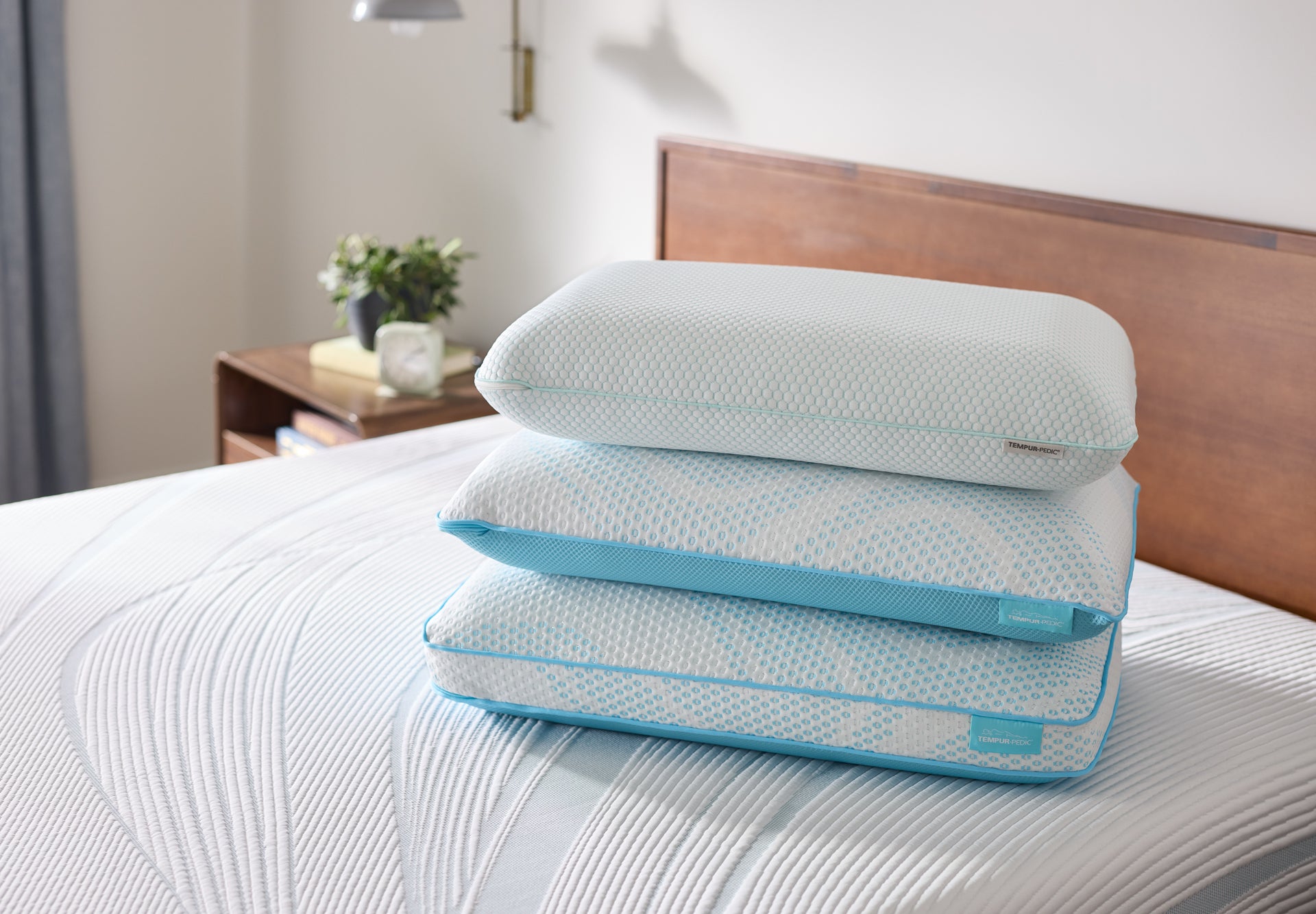 Two pillows stacked on a bed with a wooden headboard and nightstand in the background.