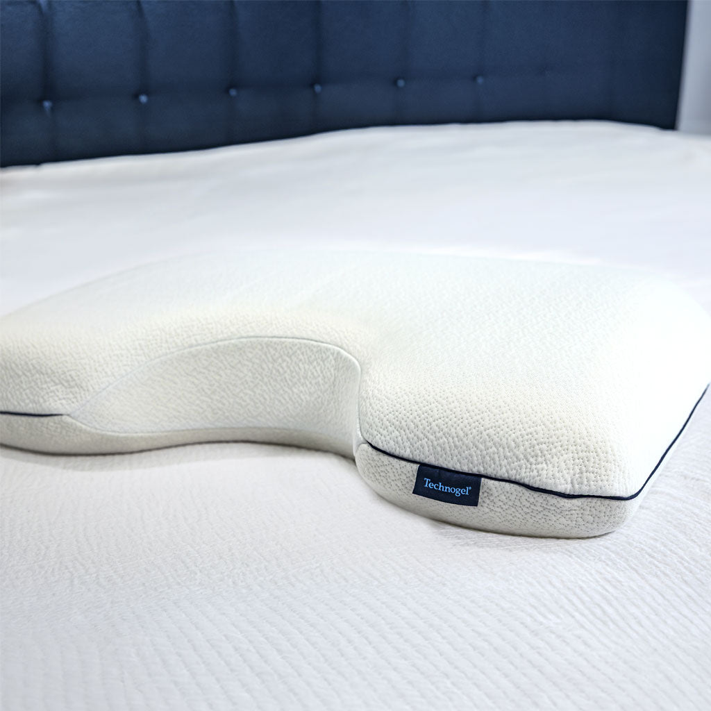 U-shaped pillow on a bed with a blue headboard
