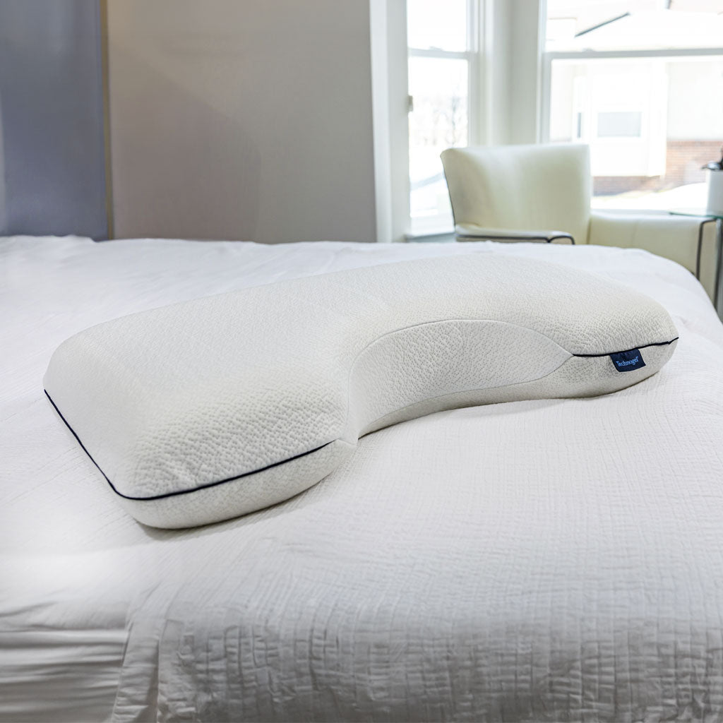 Ergonomic pillow on a bed in a bright room with large windows