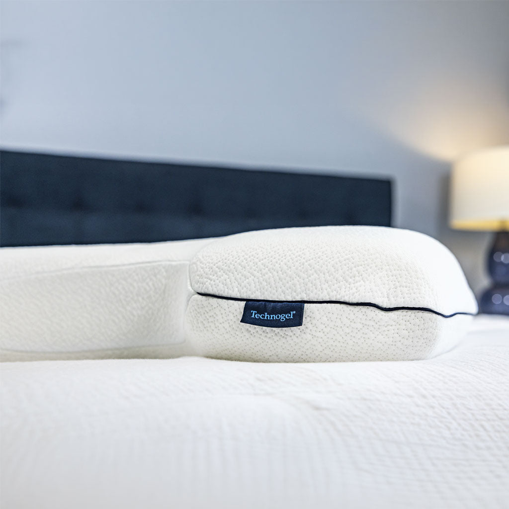 White pillow with a brand label on a bed in a bedroom setting