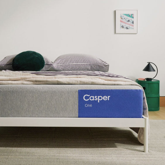 Casper mattress on a bed with pillows and bedding in a room setting.