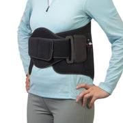 A black waist support belt worn by a model in a light blue long-sleeve top and gray pants, shown against a plain white background.