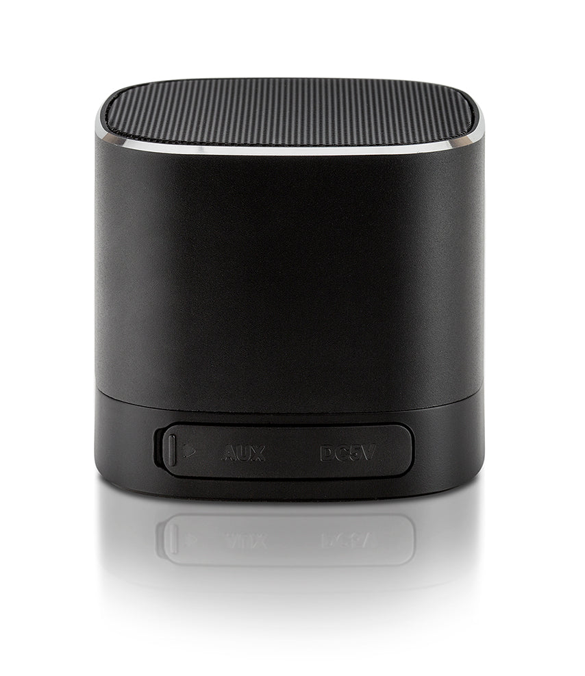 A black cylindrical portable speaker with a power button panel on the front, shown on a reflective white surface.