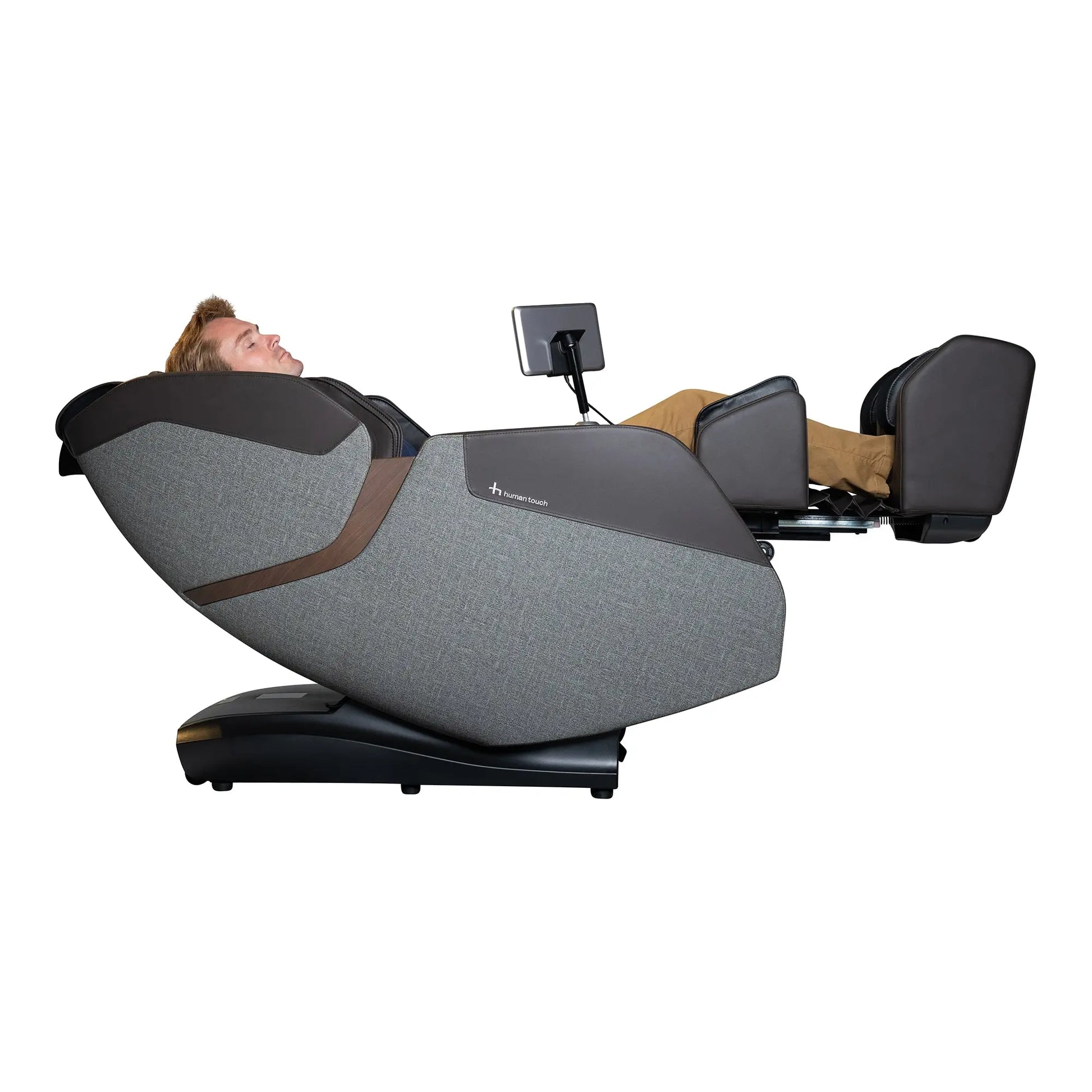 A man using the WholeBody® ROVE Massage Chair by Human Touch® with the calf and foot massager extended on a white