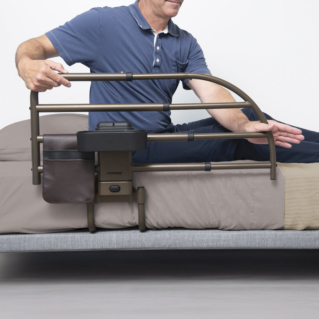 Man using a bed rail on a bed with a neutral background