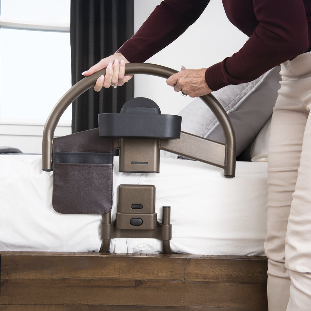 Person using a bed rail with a handrail on a bed