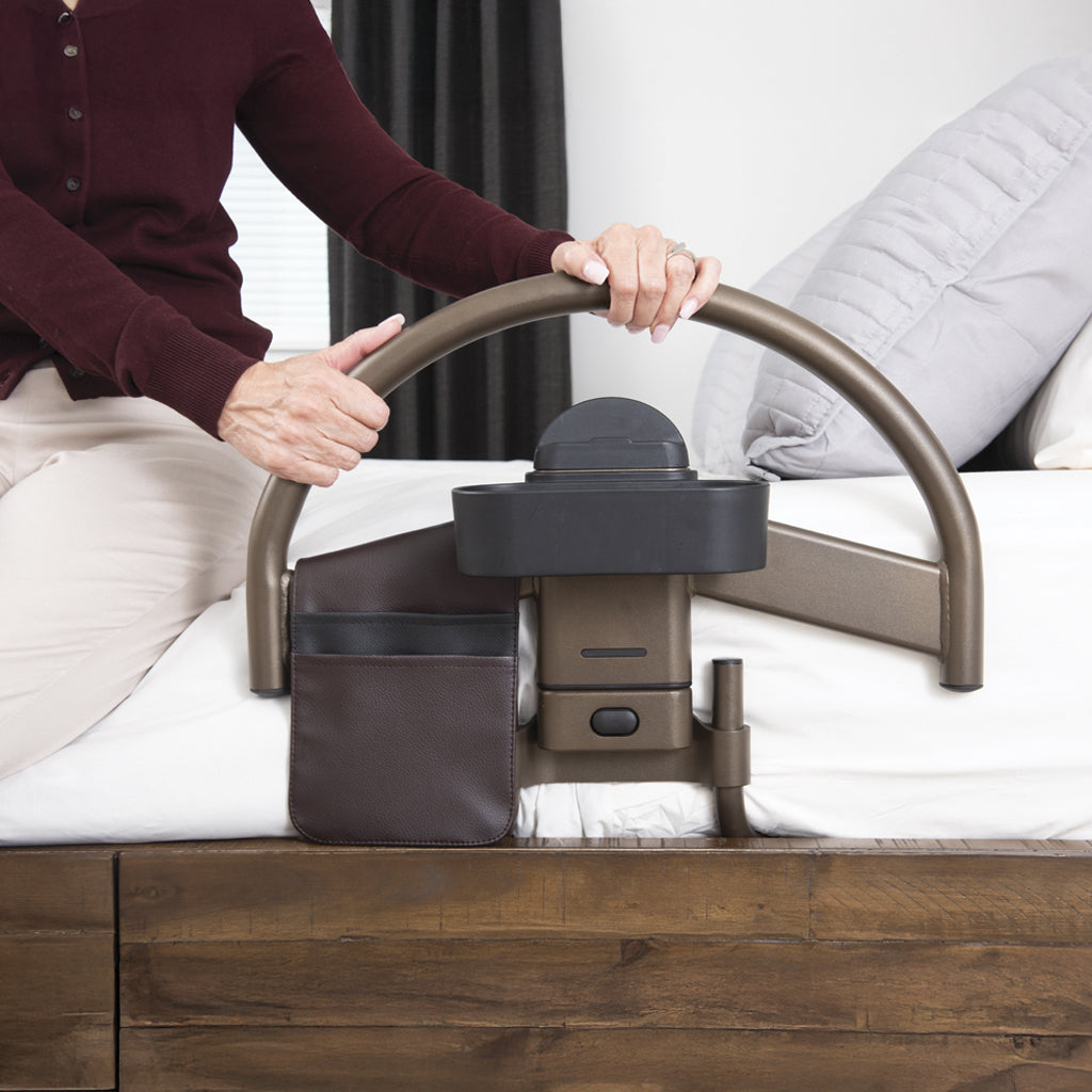 Person using a bed rail with a handrail on a bed